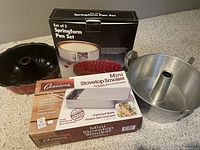 Photo showing the boxed mini stovetop smoker, boxed set of 3 springform pans, fluted pan, and an angel food cake pan