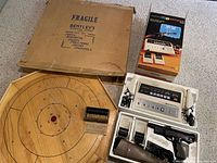 Vintage Crokinole wooden disc shooting board with original Bentley's Sporting Goods fragile box, Lloyd's Color TV Sports 813 gaming device with controls and original box beside it.