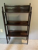 Front view of vintage wooden bookcase showing three shelves and decorative carved back panel.