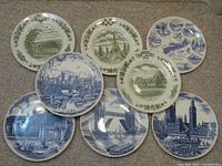 Top view of all eight decorative plates arranged on carpeted floor showing green Canadian and blue UK themed plates.