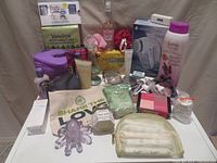 Full lot showing bath and beauty products including lotions, fabric shaver, pantiliners, cosmetics, and a purple octopus massager