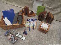Overview of entire lot showing basket with origami paper and notepaper holder with notes, wooden and onyx-like bookends, notebook with green felt cover, two blue airplane pencils, metal bookmark and pencil caps.