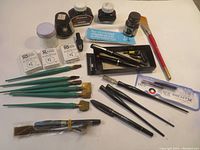 Full view of collection including all bottles, dip pens, nibs, holders, brush, booklet, and ink jars.