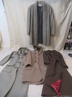 All four vintage winter coats displayed together on floor and hanging, showing color and length differences