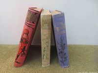 Three vintage hardcover children's annuals standing upright showing spines: Chums Annual (red cover), Blackie's Children's Annual (beige cover), The Girl's Own Annual (blue cover).