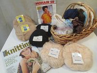 Full lot photo showing six skeins of mohair yarn in beige, black, and cream, Vogue Knitting magazine, knitting pattern, two bags of lace trim, and a wicker basket containing trims and yarn.