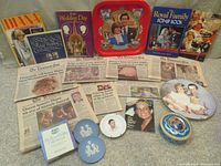 Photo showing entire collection of memorabilia items including newspapers, plates, tins, books, and magazines related to Prince Charles and Princess Diana