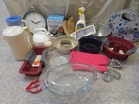 Photo showing variety of kitchen ware items including pans, glass casserole, oven mitts, and kitchen tools