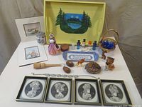 Wide view of entire assortment showing tray, framed art, ceramic figurines, glassware, wooden items, necklace, and other trinkets.