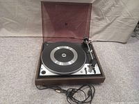 Full view of the turntable with dust cover open showing wood casing and platter.