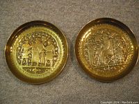 Pair of brass wall plaques side by side on carpeted floor showing overall size and depth