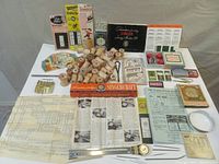Overview of a large group of vintage sewing items displayed on a tabletop. Includes wooden thread spools, instruction booklets, sewing tapes, and vintage notions.