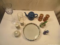 Full table display showing all items in the lot including Wedgwood dishes, enamel teapot, glass votive holder, drinking glass, wood candlestick holders, and bird ornaments.
