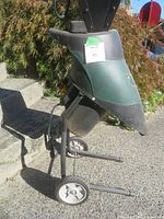 Full view of green Yard Works electric garden shredder mounted on wheeled legs with funnel-shaped intake and extended power cord.