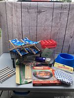 Full lot on a table with wooden backdrop showing all items: chairs, table, drink holders, bird heated bowl and miscellaneous items.