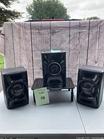 Sony CD stereo system main unit centered with two matching Sony speakers on either side on a table outdoors.