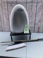 Front view of Eye-Vac vacuum on stand with broom head and handle laid in front