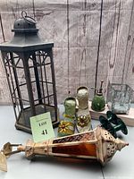 Photo of the entire lot showing all items including lanterns, decorative shoes, plant mister, glass container, and hose stakes.