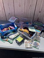 Wide view of the lot showing containers labeled Headbands, Head Scarves, Masks Headbands, and multiple accessory items spread out on a table including mirrors and products in packaging.