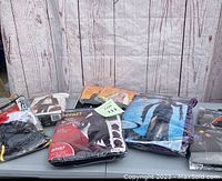 Five Halloween costumes in original packaging displayed on a table. Costumes include scary themed characters with capes and wigs.