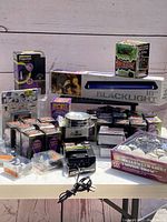 Photo showing the grouped Halloween lighting bulbs, blacklight tube, strobe, sound machine, and Halloween CDs on a table outside.