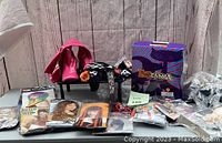 Photo of Halloween wigs, pink boots, temporary tattoos, and masks on a grey table against a wooden backdrop
