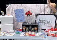 Photo showing the entire lot including cards, tins, glassware, framed rollercoaster art print, cooler boxes, flower arrangement, hat, and garden flag.