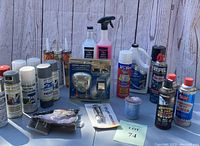 Photo of assorted spray paint cans, sealant tubes, and automotive cleaning products arranged on a table