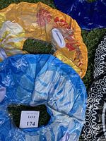 Top view of three pool floats: yellow with red floral pattern, blue and white with white handles, and black and white geometric pattern, displayed on grass.