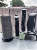 Photo showing four units: two Lasko heaters, one Holmes heater, one Sharper Image air purifier, all standing on a white table against a backdrop
