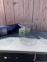 Lot display on white table with wooden paneled background showing all glass items and box