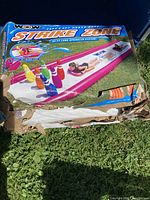 Photo of the damaged box packaging showing the brand and product name 'WOW Strike Zone' water slide with bowling pin graphics.