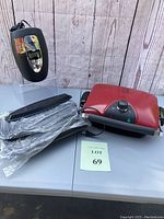 Photo displaying the red George Foreman grill with attached power cord and black Waring Pro electric wine chiller with digital display.