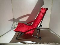 Side view of one red Showtime camp chair showing fabric seat and padded armrests.