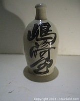 Front side of the ceramic jug showing detailed Japanese calligraphy characters in black.