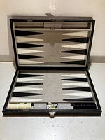 Folded open backgammon board with white and black playing pieces and four dice in center.