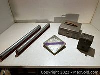 Lot showing the two metal rollers, gray metal box with handle and latch, black box with dials, and square plastic dado blade case