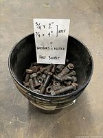 Half bucket filled with assorted heavy-duty 3/4-inch bolts, washers, and nuts with a note describing bolt sizes.