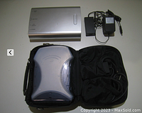 Silver external drive enclosure, power adapters, and black soft carrying case holding an optical drive and cables.