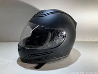 Side view of matte black full-face motorcycle helmet showing clear face shield and ventilation details.