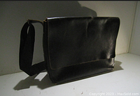 Front full view of the black leather messenger bag with flap and shoulder strap