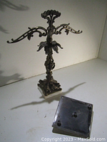 Front and side views of an antique brass necklace hanger with a detailed marble base. The brass has ornate scroll and floral designs and multiple hooks for hanging necklaces.