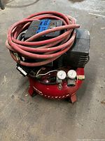 Red Porter Cable pancake air compressor with black motor housing and red air hose coiled on top.