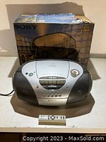 Front view of Sony portable boombox with remote control on surface in front.