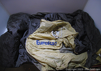 Yellow vintage Eureka tent fabric laid out over black storage bag, showing logo and condition of fabric.