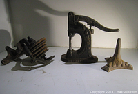 Photo showing three vintage industrial cast iron tools including a spindle tool, lever press marked BROOKFIELD, and a decorative base.