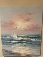 Full front view of the acrylic seashore painting showing coral colored sky, sea foam green waves, and flying seagulls.