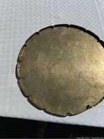 Photo of the bronze tray top side showing etched design and scalloped edges, with patina and wear marks visible.