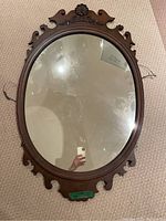 Overall view of the oval antique mirror with full frame and reflective glass, showing some surface marks.