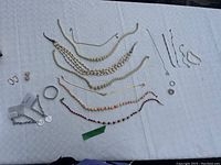 Assorted costume jewelry laid out on white textured surface including necklaces, earrings, rings, and bracelets.